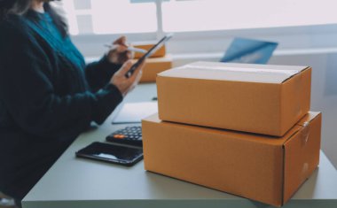 Startup SME small business entrepreneur of freelance Asian woman using a laptop with box Cheerful success Asian woman her hand lifts up online marketing packaging box and delivery SME idea concept