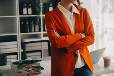 Çekici gülümseyen Asyalı iş kadını ev ofisinde çalışıyor, Asyalı kadın dizüstü bilgisayarında tablet tutuyor..