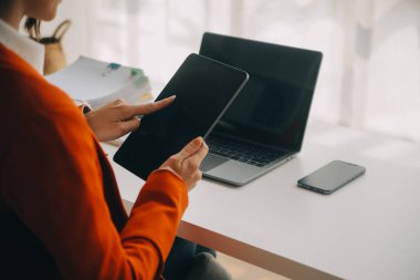 Çekici gülümseyen Asyalı iş kadını ev ofisinde çalışıyor, Asyalı kadın dizüstü bilgisayarında tablet tutuyor..