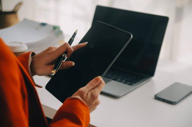 Çekici gülümseyen Asyalı iş kadını ev ofisinde çalışıyor, Asyalı kadın dizüstü bilgisayarında tablet tutuyor..