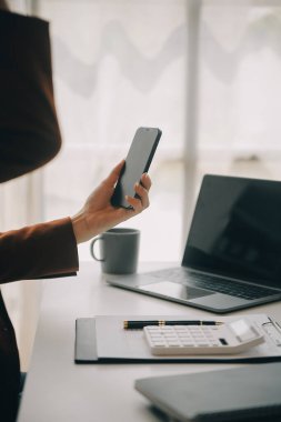 Çekici gülümseyen Asyalı iş kadını ev ofisinde çalışıyor, Asyalı kadın dizüstü bilgisayarında tablet tutuyor..