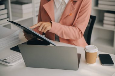 Hesap makinesi ve dizüstü bilgisayarı kullanarak ahşap masa, vergi, muhasebe, istatistik ve analitik araştırma konseptine matematik finansmanı sağlayan İş kadını kapat