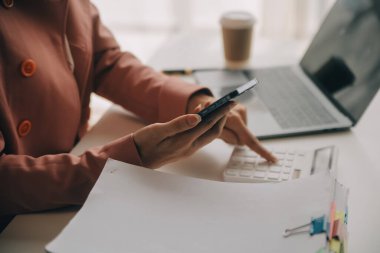 Hesap makinesi ve dizüstü bilgisayarı kullanarak ahşap masa, vergi, muhasebe, istatistik ve analitik araştırma konseptine matematik finansmanı sağlayan İş kadını kapat
