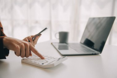 Hesap makinesi ve dizüstü bilgisayarı kullanarak ahşap masa, vergi, muhasebe, istatistik ve analitik araştırma konseptine matematik finansmanı sağlayan İş kadını kapat