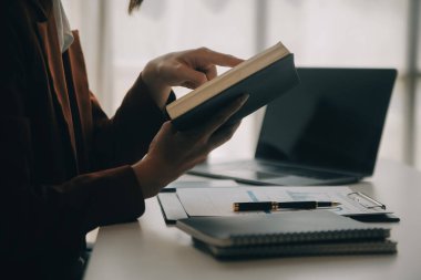 Hesap makinesi ve dizüstü bilgisayarı kullanarak ahşap masa, vergi, muhasebe, istatistik ve analitik araştırma konseptine matematik finansmanı sağlayan İş kadını kapat