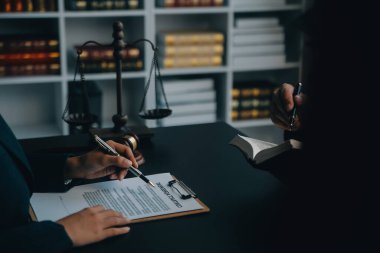 Adalet ve hukuk kavramı. Bir mahkeme salonunda tokmakla çalışan, bilgisayar ve kenetlenme klavyesi, gözlük takan bir erkek yargıç, sabah ışığında masada.
