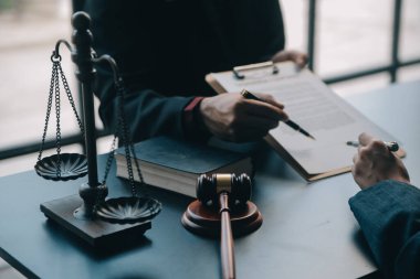 Adalet ve hukuk kavramı. Bir mahkeme salonunda tokmakla çalışan, bilgisayar ve kenetlenme klavyesi, gözlük takan bir erkek yargıç, sabah ışığında masada.