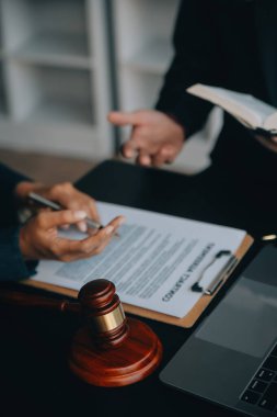 Adalet ve hukuk kavramı. Bir mahkeme salonunda tokmakla çalışan, bilgisayar ve kenetlenme klavyesi, gözlük takan bir erkek yargıç, sabah ışığında masada.