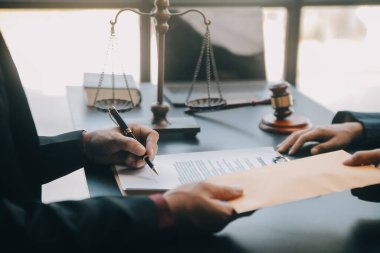 Adalet ve hukuk kavramı. Bir mahkeme salonunda tokmakla çalışan, bilgisayar ve kenetlenme klavyesi, gözlük takan bir erkek yargıç, sabah ışığında masada.