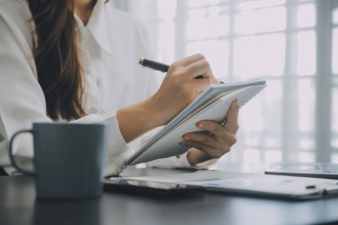 Asyalı iş kadını dizüstü bilgisayar kullanıyor ve ofiste hesap makinesi ile çalışıyor, mali raporu, iş planı yatırımını, mali analiz konseptini analiz etmeyi planlıyor..