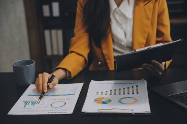 Asyalı iş kadını dizüstü bilgisayar kullanıyor ve ofiste hesap makinesi ile çalışıyor, mali raporu, iş planı yatırımını, mali analiz konseptini analiz etmeyi planlıyor..