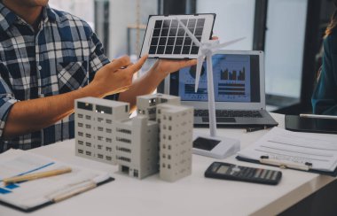 Elektrik mühendisi ve iş adamı binanın çatısındaki yeni güneş pili panelini tartışıyorlar. Alternatif enerji kavramı.