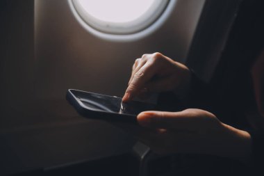 Sarışın kadın turist gelen bildirim netbook ile uçak koltuğunda oturan Smartphone cep telefonu ile kontrol. Genç işkadını paylaşmak medya telefonu dizüstü bilgisayar üzerinde uçak uçuş sırasında
