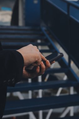 Uluslararası havaalanındaki genç Asyalı kadın, cep telefonu kullanıyor ve uçuş bilgilerini kontrol ediyor.