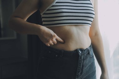 Kadın göbeği. Şişman kadın göbek yağlarını tutuyor. diyet yaşam tarzı konsepti karın kaslarını zayıflatmak ve sağlıklı mide kaslarını şekillendirmek için.