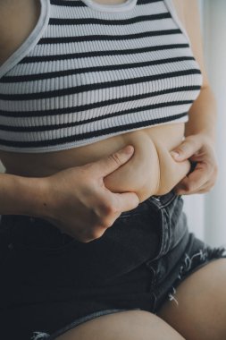 Kadın göbeği. Şişman kadın göbek yağlarını tutuyor. diyet yaşam tarzı konsepti karın kaslarını zayıflatmak ve sağlıklı mide kaslarını şekillendirmek için.