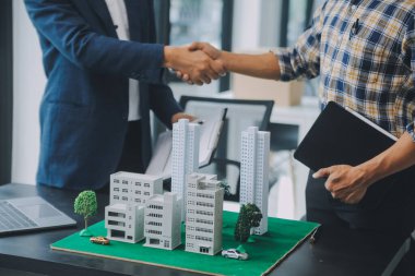 Emlak komisyoncusu müşteriye bir model ev örneği, ipotek sözleşmesi ev kiralama ve satın alma ve satma ve ipotek kredisi konsepti verir.