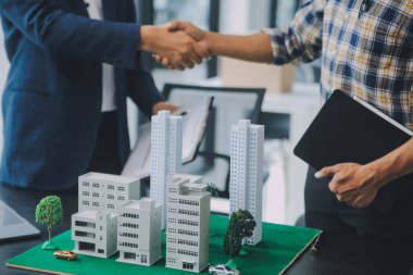 Emlak komisyoncusu müşteriye bir model ev örneği, ipotek sözleşmesi ev kiralama ve satın alma ve satma ve ipotek kredisi konsepti verir.