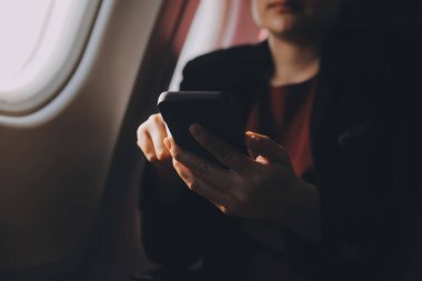 Sarışın kadın turist gelen bildirim netbook ile uçak koltuğunda oturan Smartphone cep telefonu ile kontrol. Genç işkadını paylaşmak medya telefonu dizüstü bilgisayar üzerinde uçak uçuş sırasında