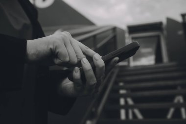 Uluslararası havaalanındaki genç Asyalı kadın, cep telefonu kullanıyor ve uçuş bilgilerini kontrol ediyor.