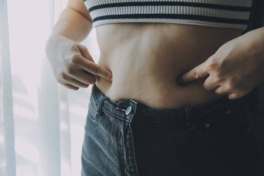 Kadın göbeği. Şişman kadın göbek yağlarını tutuyor. diyet yaşam tarzı konsepti karın kaslarını zayıflatmak ve sağlıklı mide kaslarını şekillendirmek için.