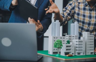 Emlak komisyoncusu müşteriye bir model ev örneği, ipotek sözleşmesi ev kiralama ve satın alma ve satma ve ipotek kredisi konsepti verir.