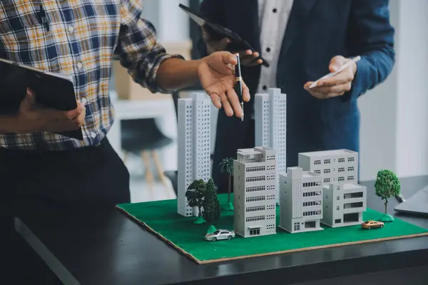Emlak komisyoncusu müşteriye bir model ev örneği, ipotek sözleşmesi ev kiralama ve satın alma ve satma ve ipotek kredisi konsepti verir.