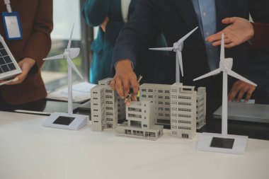 Tablete yakın çekim, Mühendisler tableti elleriyle işaret ediyorlar. Rüzgar ve güneş enerjisiyle yenilenebilir enerji kullanımını ortaklaşa tasarlamak için. Yenilenebilir enerji kullanma kavramı.