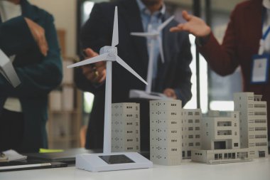 Tablete yakın çekim, Mühendisler tableti elleriyle işaret ediyorlar. Rüzgar ve güneş enerjisiyle yenilenebilir enerji kullanımını ortaklaşa tasarlamak için. Yenilenebilir enerji kullanma kavramı.