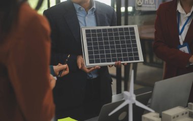 Tablete yakın çekim, Mühendisler tableti elleriyle işaret ediyorlar. Rüzgar ve güneş enerjisiyle yenilenebilir enerji kullanımını ortaklaşa tasarlamak için. Yenilenebilir enerji kullanma kavramı.