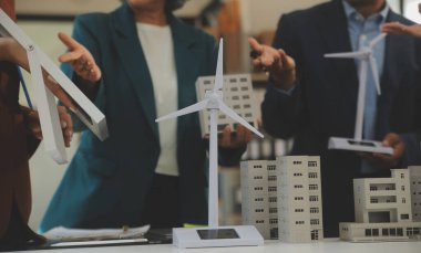 Tablete yakın çekim, Mühendisler tableti elleriyle işaret ediyorlar. Rüzgar ve güneş enerjisiyle yenilenebilir enerji kullanımını ortaklaşa tasarlamak için. Yenilenebilir enerji kullanma kavramı.