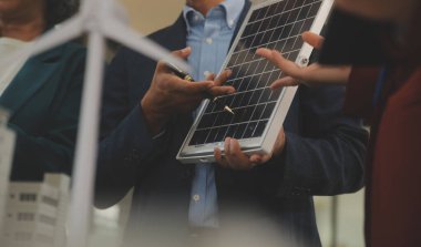 Tablete yakın çekim, Mühendisler tableti elleriyle işaret ediyorlar. Rüzgar ve güneş enerjisiyle yenilenebilir enerji kullanımını ortaklaşa tasarlamak için. Yenilenebilir enerji kullanma kavramı.