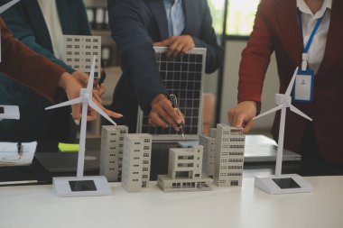 Tablete yakın çekim, Mühendisler tableti elleriyle işaret ediyorlar. Rüzgar ve güneş enerjisiyle yenilenebilir enerji kullanımını ortaklaşa tasarlamak için. Yenilenebilir enerji kullanma kavramı.