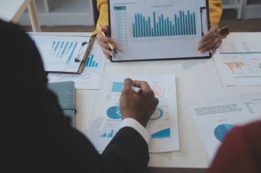 Finansal analistler, şirketlerin başarılı takım çalışmalarının sonuçlarını gösteren bir toplantıda bir dijital tablet planlama yatırım projesinin ticari mali raporlarını analiz ediyorlar..