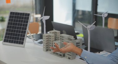 Tablete yakın çekim, Mühendisler tableti elleriyle işaret ediyorlar. Rüzgar ve güneş enerjisiyle yenilenebilir enerji kullanımını ortaklaşa tasarlamak için. Yenilenebilir enerji kullanma kavramı.