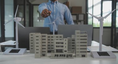 Tablete yakın çekim, Mühendisler tableti elleriyle işaret ediyorlar. Rüzgar ve güneş enerjisiyle yenilenebilir enerji kullanımını ortaklaşa tasarlamak için. Yenilenebilir enerji kullanma kavramı.