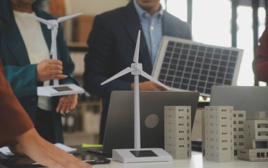 Tablete yakın çekim, Mühendisler tableti elleriyle işaret ediyorlar. Rüzgar ve güneş enerjisiyle yenilenebilir enerji kullanımını ortaklaşa tasarlamak için. Yenilenebilir enerji kullanma kavramı.