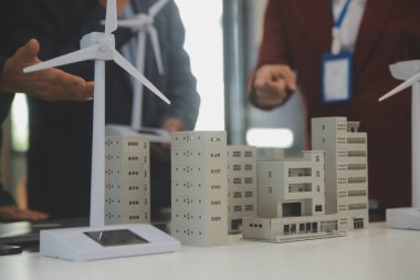 Tablete yakın çekim, Mühendisler tableti elleriyle işaret ediyorlar. Rüzgar ve güneş enerjisiyle yenilenebilir enerji kullanımını ortaklaşa tasarlamak için. Yenilenebilir enerji kullanma kavramı.