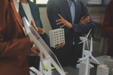 Tablete yakın çekim, Mühendisler tableti elleriyle işaret ediyorlar. Rüzgar ve güneş enerjisiyle yenilenebilir enerji kullanımını ortaklaşa tasarlamak için. Yenilenebilir enerji kullanma kavramı.