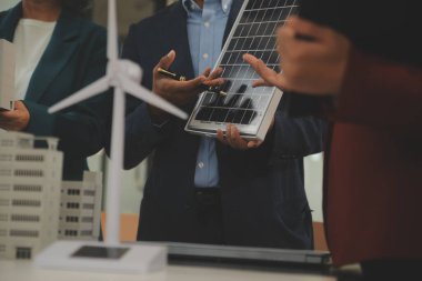 Tablete yakın çekim, Mühendisler tableti elleriyle işaret ediyorlar. Rüzgar ve güneş enerjisiyle yenilenebilir enerji kullanımını ortaklaşa tasarlamak için. Yenilenebilir enerji kullanma kavramı.