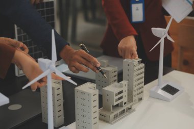 Tablete yakın çekim, Mühendisler tableti elleriyle işaret ediyorlar. Rüzgar ve güneş enerjisiyle yenilenebilir enerji kullanımını ortaklaşa tasarlamak için. Yenilenebilir enerji kullanma kavramı.