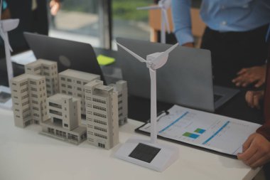 Tablete yakın çekim, Mühendisler tableti elleriyle işaret ediyorlar. Rüzgar ve güneş enerjisiyle yenilenebilir enerji kullanımını ortaklaşa tasarlamak için. Yenilenebilir enerji kullanma kavramı.