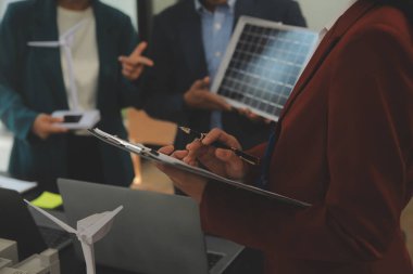 Tablete yakın çekim, Mühendisler tableti elleriyle işaret ediyorlar. Rüzgar ve güneş enerjisiyle yenilenebilir enerji kullanımını ortaklaşa tasarlamak için. Yenilenebilir enerji kullanma kavramı.