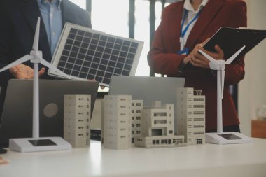 Tablete yakın çekim, Mühendisler tableti elleriyle işaret ediyorlar. Rüzgar ve güneş enerjisiyle yenilenebilir enerji kullanımını ortaklaşa tasarlamak için. Yenilenebilir enerji kullanma kavramı.