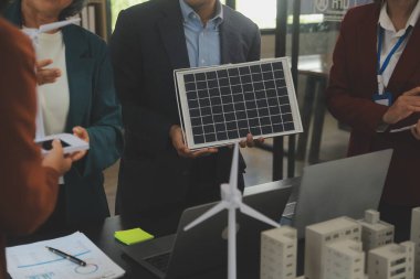 Tablete yakın çekim, Mühendisler tableti elleriyle işaret ediyorlar. Rüzgar ve güneş enerjisiyle yenilenebilir enerji kullanımını ortaklaşa tasarlamak için. Yenilenebilir enerji kullanma kavramı.