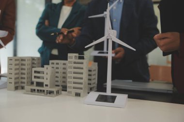 Tablete yakın çekim, Mühendisler tableti elleriyle işaret ediyorlar. Rüzgar ve güneş enerjisiyle yenilenebilir enerji kullanımını ortaklaşa tasarlamak için. Yenilenebilir enerji kullanma kavramı.