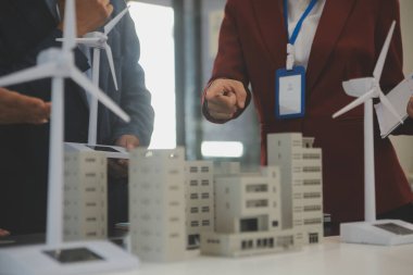 Tablete yakın çekim, Mühendisler tableti elleriyle işaret ediyorlar. Rüzgar ve güneş enerjisiyle yenilenebilir enerji kullanımını ortaklaşa tasarlamak için. Yenilenebilir enerji kullanma kavramı.