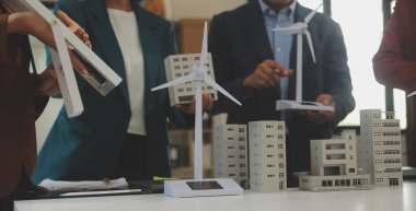 Tablete yakın çekim, Mühendisler tableti elleriyle işaret ediyorlar. Rüzgar ve güneş enerjisiyle yenilenebilir enerji kullanımını ortaklaşa tasarlamak için. Yenilenebilir enerji kullanma kavramı.