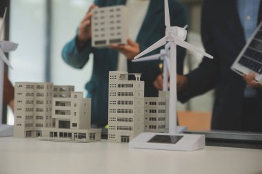 Tablete yakın çekim, Mühendisler tableti elleriyle işaret ediyorlar. Rüzgar ve güneş enerjisiyle yenilenebilir enerji kullanımını ortaklaşa tasarlamak için. Yenilenebilir enerji kullanma kavramı.