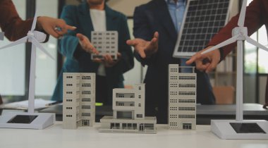 Tablete yakın çekim, Mühendisler tableti elleriyle işaret ediyorlar. Rüzgar ve güneş enerjisiyle yenilenebilir enerji kullanımını ortaklaşa tasarlamak için. Yenilenebilir enerji kullanma kavramı.